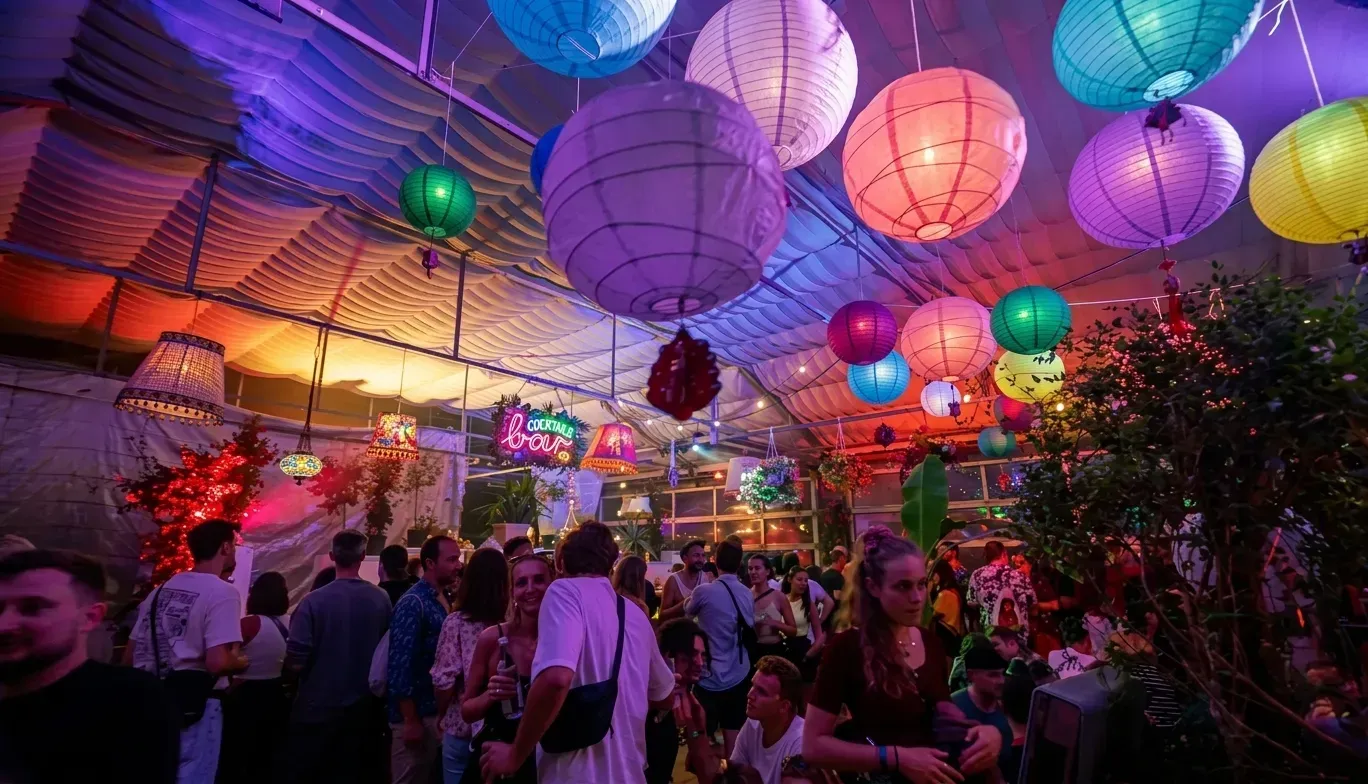 Bunte Papierlampions unter dem Gew&auml;chshausdach, darunter die Cocktailbar